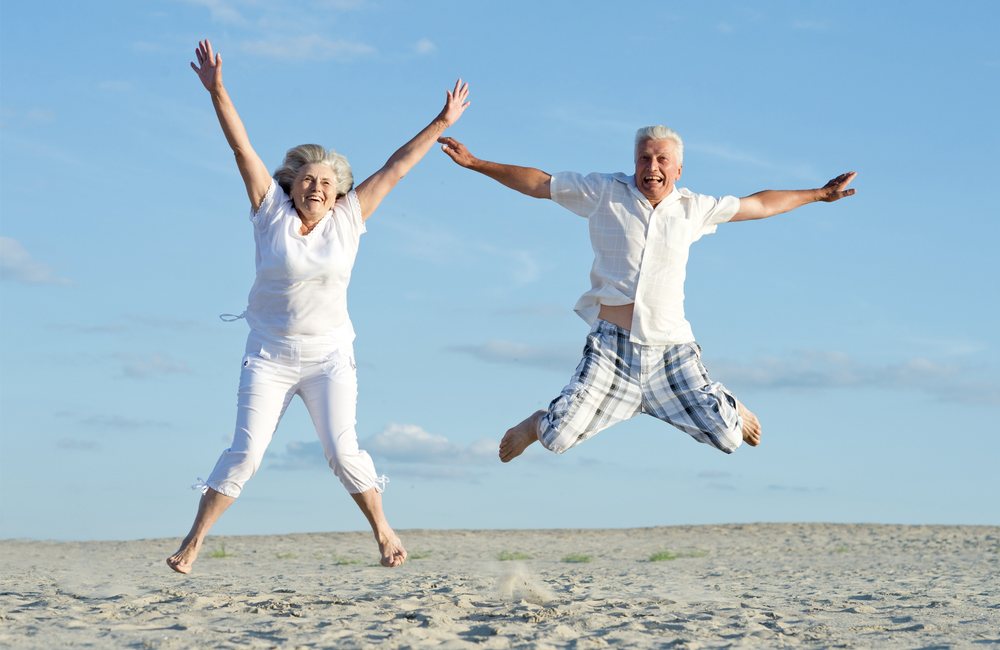 Active older couple jumping outdoors